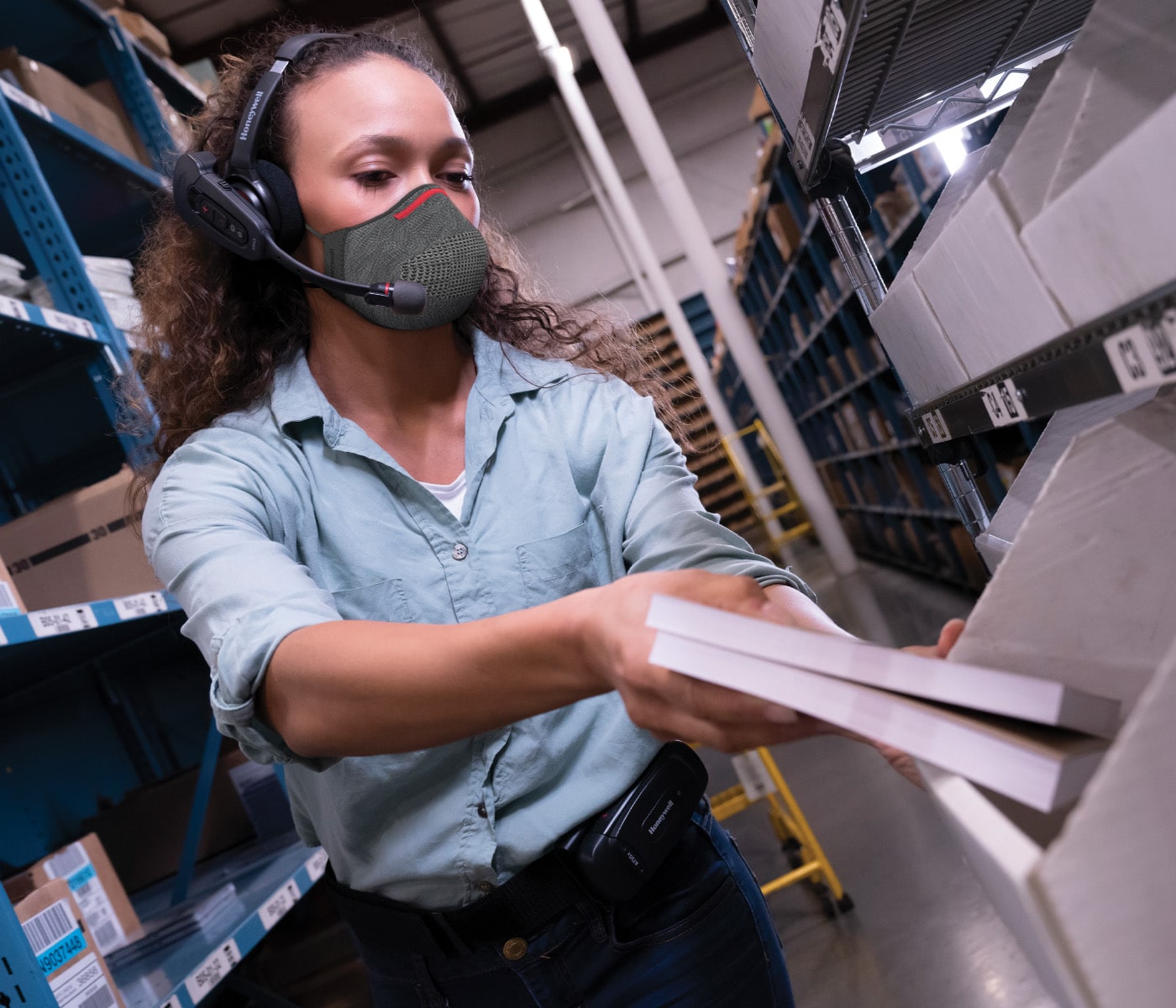 Woman with in a warehouse with a headset moving bins